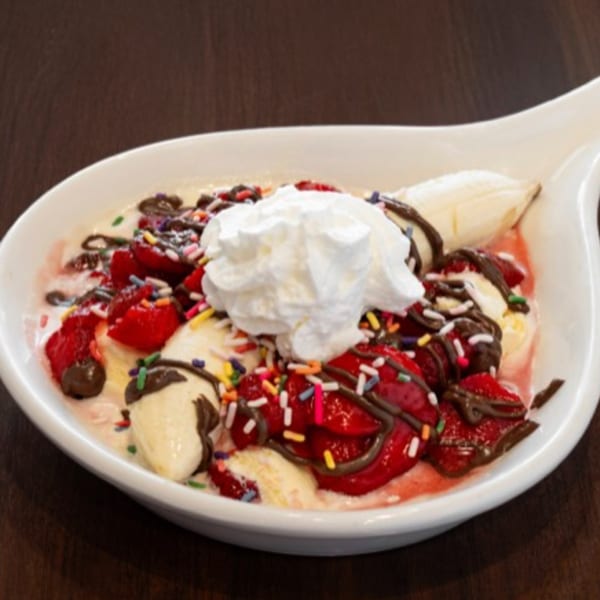 Louie's Waffle House fruit bowl with strawberries, bananas, whipped cream, chocolate drizzle, and sprinkles.