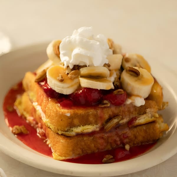 Louie's Waffle House French toast topped with bananas, whipped cream, pecans, and raspberry sauce.