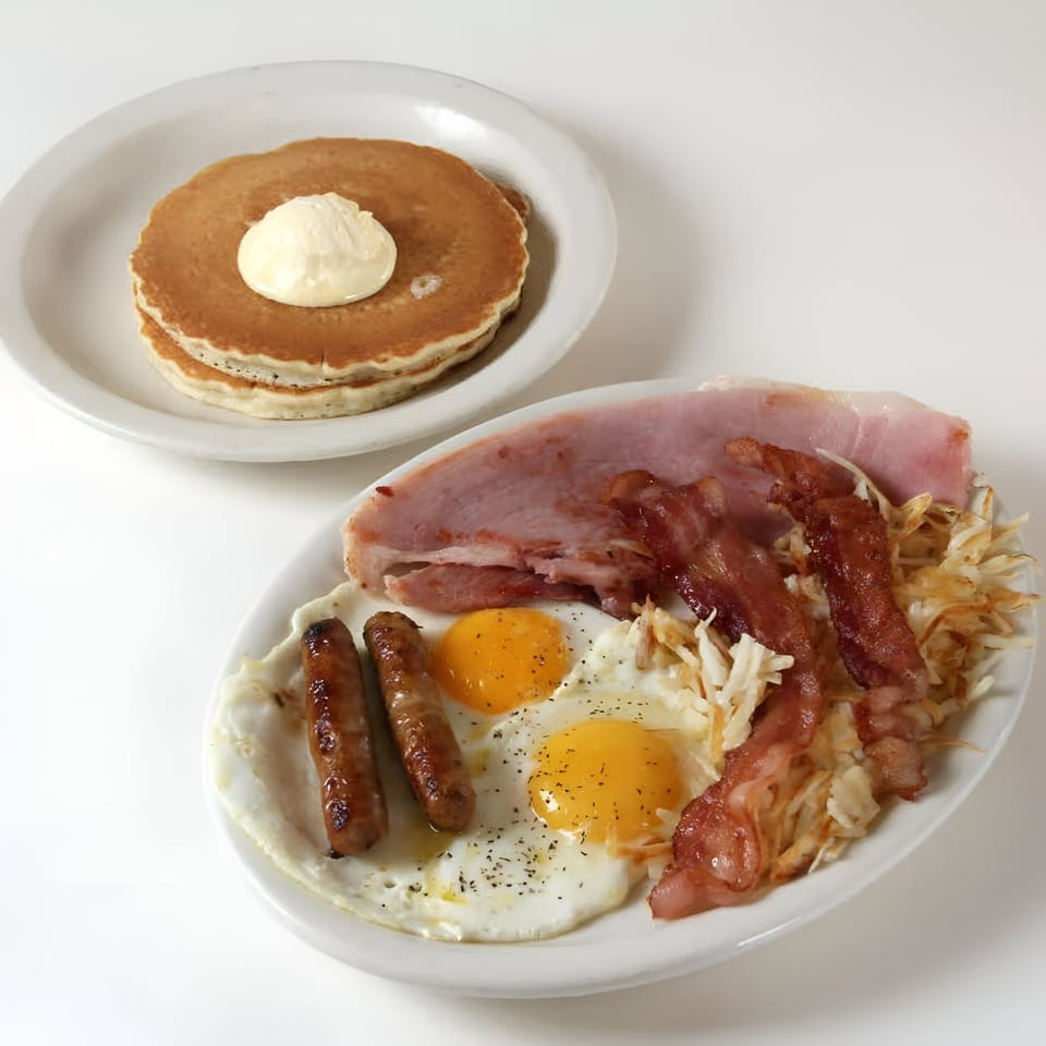 A Louie's Waffle House breakfast with pancakes, eggs, sausage, bacon, ham, and hash browns.
