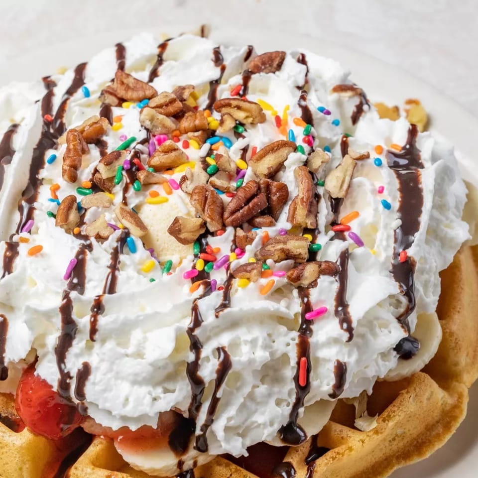 Louie's Waffle House waffle topped with whipped cream, chocolate syrup, pecans, and sprinkles.