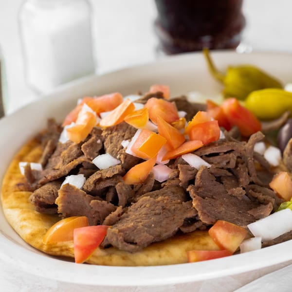 Louie's Waffle House gyro with sliced meat, diced tomatoes, and onions on pita bread.