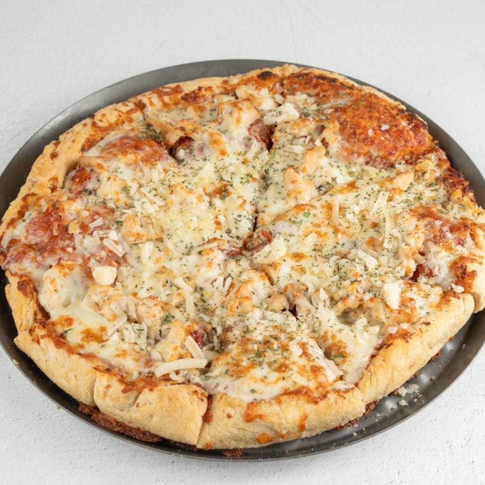 A whole breakfast pizza from Louie's Waffle House, topped with cheese, sausage, and herbs.