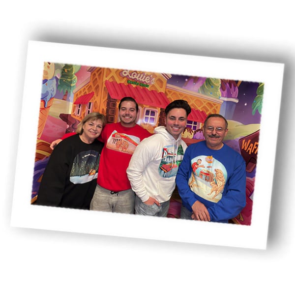 Four people smiling in front of a colorful cartoon waffle house backdrop.