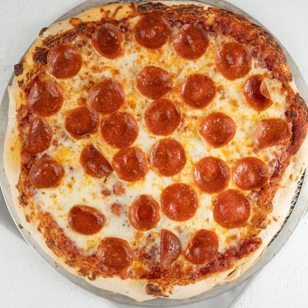 A whole pepperoni pizza with melted cheese and a crispy crust on a metal pan.