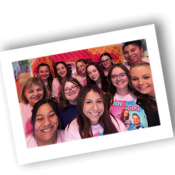 Smiling Louie's Waffle House staff members in pink shirts pose together for a group photo.
